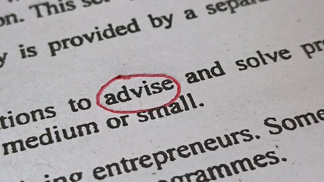 Closeup of hand with red ink pen mark circle around to emphasize or highlight advise word print on paper. Person focus and outline advise text symbolic concept.