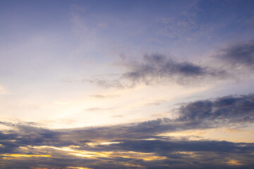 Fototapeta premium Serene Twilight Sky with Soft Sunset Glow and Dark Clouds,A peaceful outdoor landscape photograph of a twilight sky featuring dark soft clouds illuminated by a golden sunset glow along the horizon.