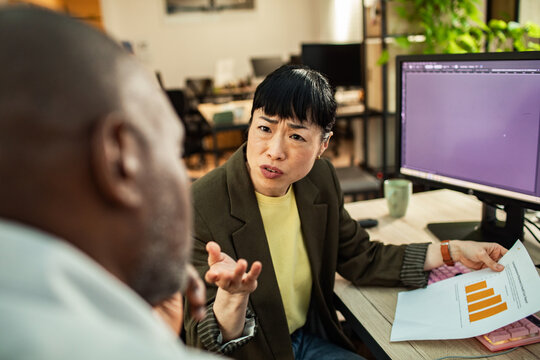 Woman questioning colleague about data report in office