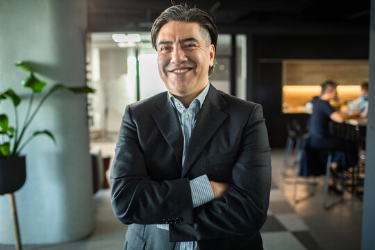 Smiling businessman with arms crossed in modern office