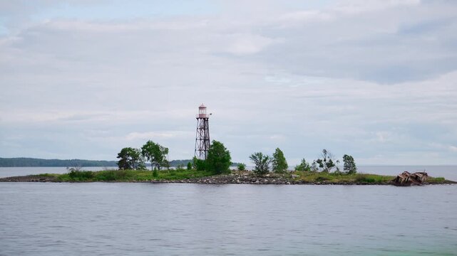 Lighthouse on small rocky island in lake, view from boat, Karelia northern landscape