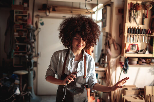 Woman dancing to music in woodworking workshop