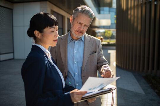 Business colleagues reviewing documents outside an office building