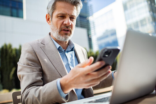 Businessman frustrated with smartphone while working outdoors