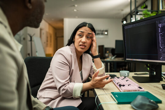 Frustrated designer explaining issue to colleague at computer