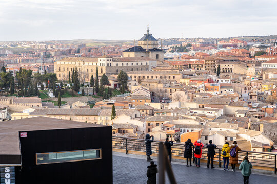 Toledo, Castile-La Mancha, Spain - 23 January 2020: View of the historic cityscape with traditional stone buildings, terracotta rooftops, and a church dome, with people at a viewpoint.