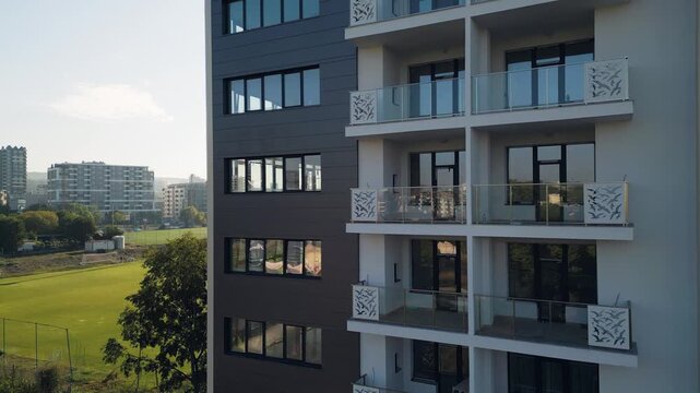 Modern residential building facade with glass reflections and decorative balconies