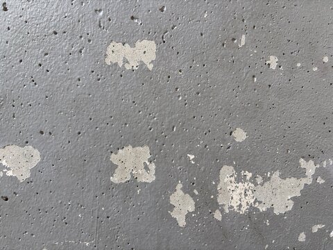 Chipped grey paint exposing rough concrete patches with pinholes background