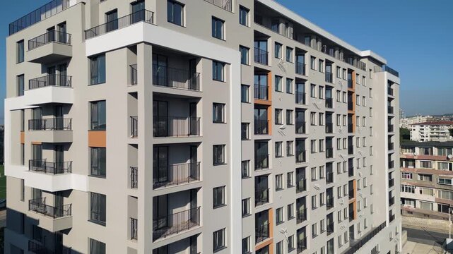 Modern residential building facade with grey panels, balconies and blue sky