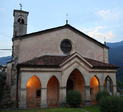 Historic Chiesa di San Rocco church in Bagolino, Lombardy, Italy. Beautiful medieval stone church with illuminated arches, portico and bell tower in Brescian Prealps.