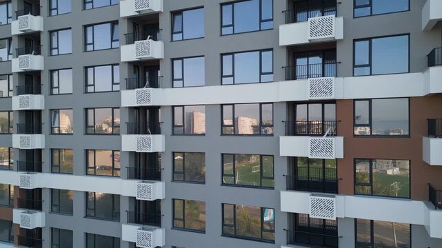 Modern apartment building facade with white balconies and glass reflections
