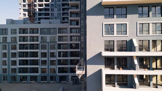 Construction hoist moving up between modern multi-story residential buildings