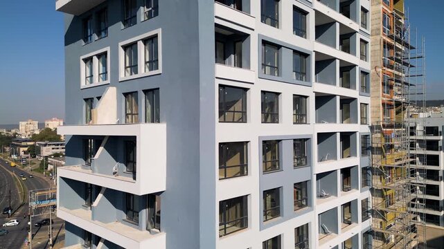 Modern apartment building facade under construction with scaffolding and clear sky