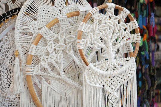 Handmade white macrame dreamcatcher displayed at colorful artisan craft market