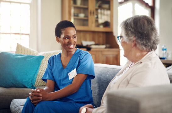 Happy, caregiver and old woman in care home with conversation, wellness check and social support. Assisted living, senior patient and carer in lounge with talking, companionship and medical service
