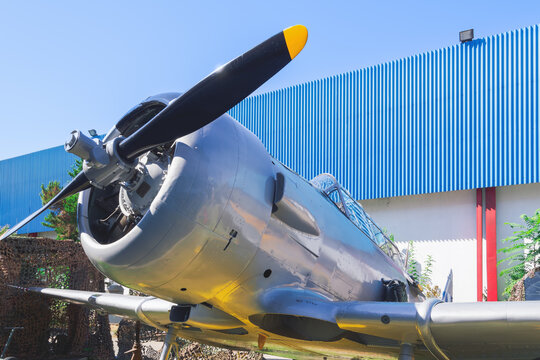 Greece - 06 September 2026: View of a vintage propeller aircraft parked outdoors with a blue hangar in the background.