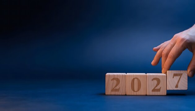 Hand completing year 2027 wooden blocks.