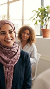 Smiling muslim businesswoman speaking in bright modern office meeting
