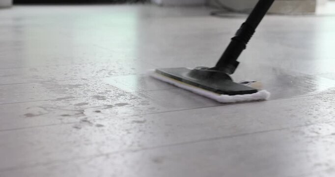 Cleaning parquet floor with modern hot steam mop in apartment. Innovative appliance used to keep house sterile and remove dirt from floor surface