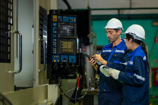 Team of caucasian mechanic engineer workers in safety equipment beside the automatic lathe machine in manufacturing factory for calibration and inspection