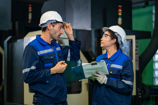 Team of industrial worker is checking the setup value of  metal casting machine by automated monitor while working inside factory for safety industry