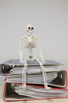 Skeleton Figure on Stacked Binders With Vertical Copy Space