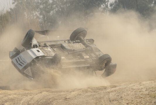 Derawar, Punjab, Pakistan - 28 November 2021: View of a rally car flipping over during the Cholistan Jeep Rally, kicking up a large cloud of dust on the sandy track.