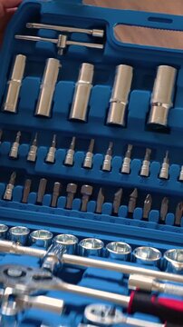Hands closing a blue plastic toolbox with a professional socket wrench and screwdriver tool set inside, close-up of mechanic equipment for automotive repair and DIY maintenance