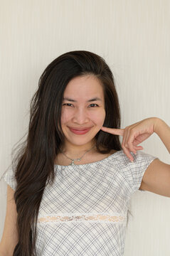 Young Woman Smiling Playfully with Hand Near Her Face in Casual Attire