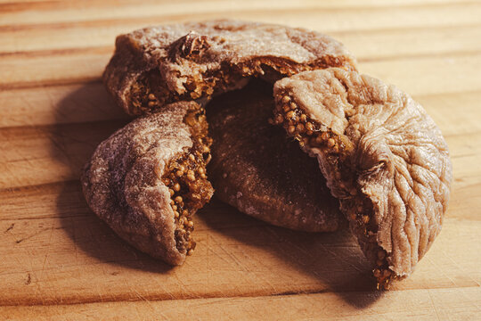 Dried fig half showing sweet sugary pulp with seeds, fresh healthy snack for nutrition and energy, isolated on wooden background . Ideal for food design and diet concepts