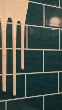 Creamy Beige Paint Drips Smoothly Down Dark Blue Glossy Ceramic Tile Wall Background