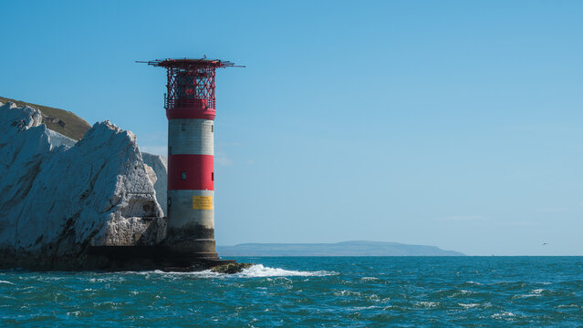 Alum Bay, England, United Kingdom - 05 September 2026: View of The Needles Lighthouse standing against white chalk cliffs and the blue sea under a clear sky.