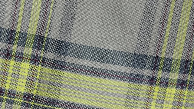 Yellow and grey plaid tartan fabric slowly waving with a soft cloth texture. Macro of a detailed textile pattern for a background
