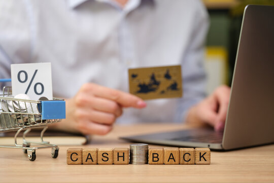 A person reviews their cashback options at a desk, holding a credit card. Nearby is a small shopping cart with promotional material. This scene highlights modern online shopping benefits.