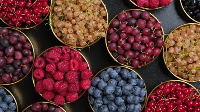 Assorted Red Currants Raspberries Blueberries Cherries and Blackberries Rotating in Golden Rimmed Bowls Concept of Healthy Eating and Fresh Fruit