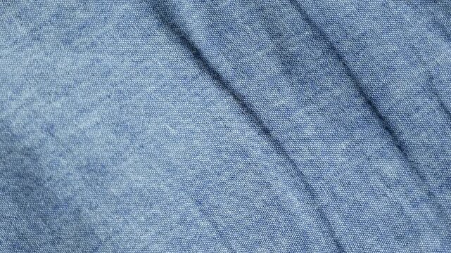 Crumpled blue denim fabric texture moving slowly in a detailed close-up. Cotton jeans textile animation background loop
