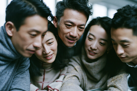 Asian Friends Leaning In and Looking Down Together