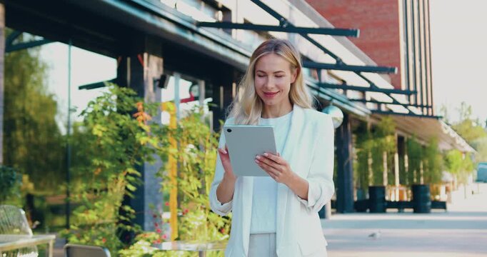 Professional businesswoman in white suit using tablet for online shopping and digital business outdoors