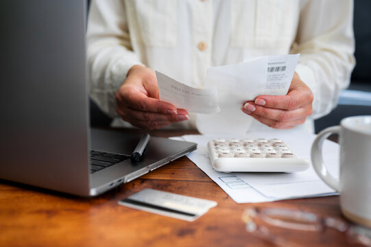 Woman reviewing receipts and calculating household expenses at home, representing personal budgeting, financial planning, bill management, spending control, accounting and everyday money decisions