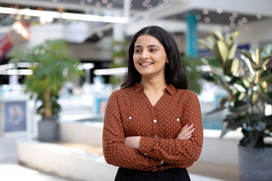Confident woman smiling with arms crossed in modern office