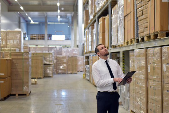 portrait friendly businessman/ manager in suit working in the warehouse of a company - control of inventories