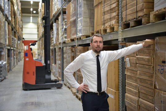portrait friendly businessman/ manager in suit working in the warehouse of a company
