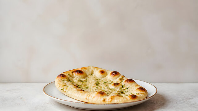 Freshly baked Indian garlic naan bread on white plate