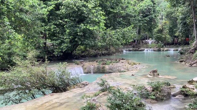 Tranquil turquoise limestone waterfall cascading into natural pools in Borneo rainforest Teluk Sulaiman Indonesia - 4K nature background