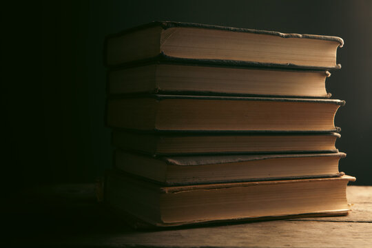 Stack of old books on wooden table. Retro style toned picture