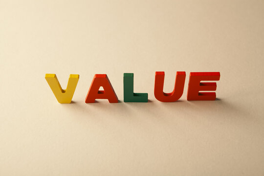 Wooden letters spelling the word value on white table.
