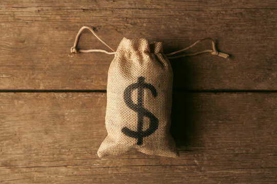 Money bag with dollar sign on wooden background.