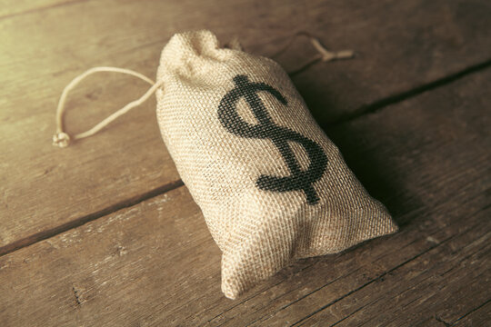 Money bag with dollar sign on wooden background.