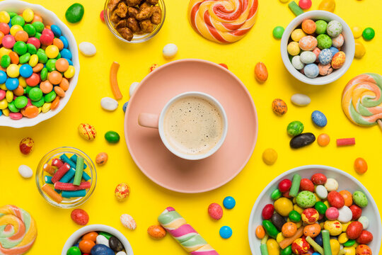 Coffee cup with chocolates and colored candy. Top view on table background with copy space