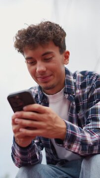 Young man smiling and typing a message on his mobile phone